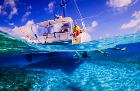 Underwater Split-Shot Of Sailing Boat And Coral Reefs Split-view photo of a sailing boat above and vibrant marine life below water.