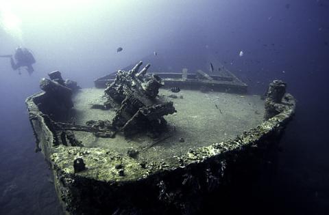Scuba Divers Explore Sunken Shipwreck Underwater Scuba divers explore sunken shipwreck with marine life on seabed.