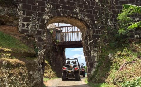 Vintage Archway With Off-Road Vehicles In Tropics Old stone archway with moss and off-road vehicles in a tropical setting