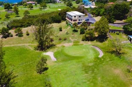 Aerial View Of Private Golf Course Estate Aerial view of a small, lush golf course with green, sand bunker, and adjacent large house