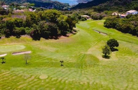 Aerial View Of Scenic Tropical Golf Course Aerial view of golf course with fairways, greens, bunkers, ponds, trees, and surrounding hills.