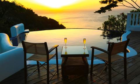 Luxurious Sunset View With Infinity Pool And Ocean Romantic sunset view with champagne on deck overlooking infinity pool and ocean.