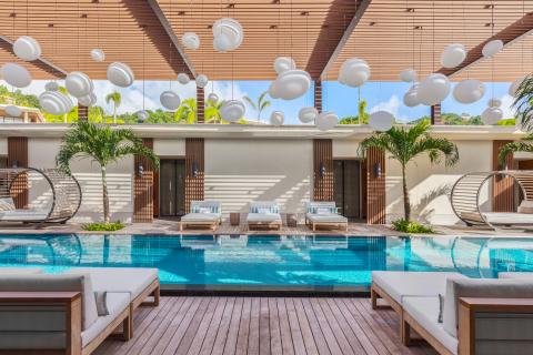 Luxury Resort Pool With Artistic Decor And Greenery Luxurious poolside with modern swings, deck chairs, and white hanging sculptures