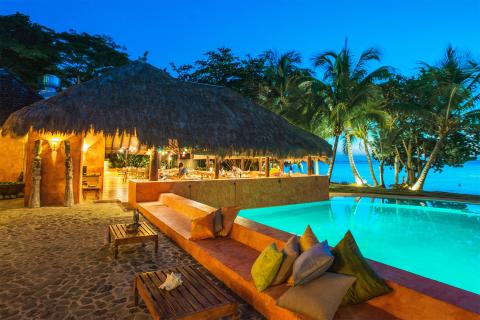 Luxurious Tropical Resort Pool And Bar At Night Luxurious tropical resort with illuminated pool and thatched-roof bar at night