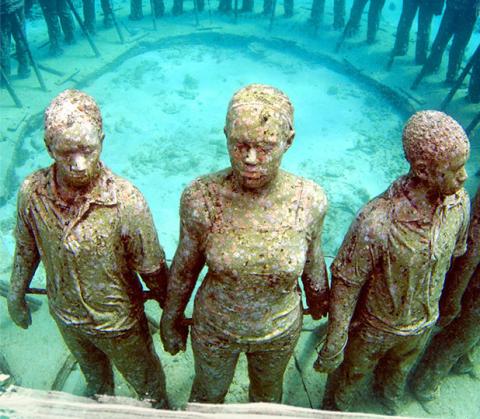 Underwater Statue Circle: Art & Reef Restoration Underwater museum with statues boosting coral reef growth, seen in clear shallow waters.