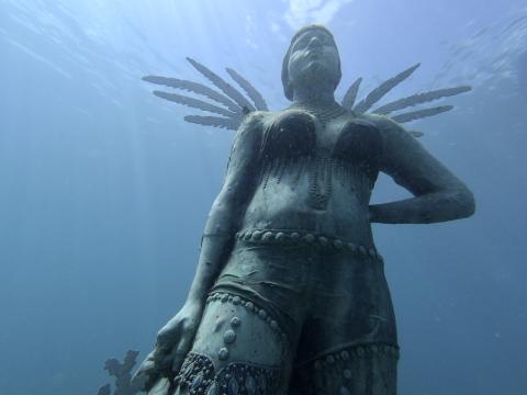 Underwater Statue Guardian Reef Art Installation Underwater statue of a winged warrior serving as an artificial reef in clear blue water