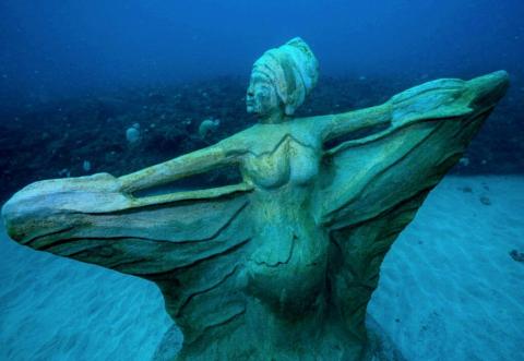 Underwater Angel Statue In Ocean For Divers Underwater statue of a winged female figure, an angel or fairy, in a dynamic pose.