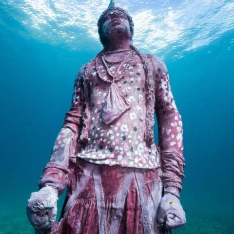 Underwater Statue In Marine Museum - Art Reef Underwater statue of a man, encrusted with marine life, in a clear, serene water setting.