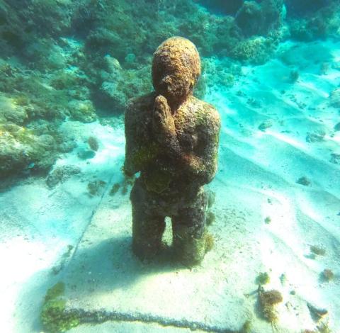 Underwater Sculpture In Reef Enhances Marine Biodiversity Underwater sculpture in a reef with clear blue water and marine growth.