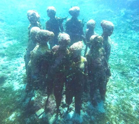 Underwater Sculpture Reef Installation With Statues Underwater sculpture garden with algae-covered statues in clear blue sea