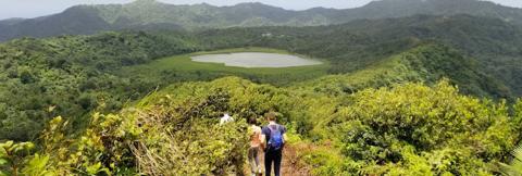 Scenic Crater Lake Hike In Lush Tropical Forest Hikers on trail overlooking crater lake in lush, tropical forest