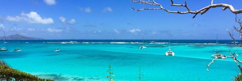 Turquoise Sea With Sailboats And Natural Frame Turquoise sea with sailboats, clear waters, and island under a scattered cloud sky