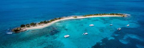 Tropical Island Paradise Aerial View For Vacation Aerial view of a tropical island with catamarans, palm trees, and turquoise waters
