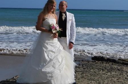 Beach Wedding Scene With Bride And Groom On Shore Beach wedding scene with bride in gown and groom in suit by the sea.