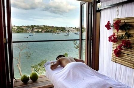Serene Spa Massage Table Overlooking Harbor View Spa massage table scene with harbor view, green apples, and floral decor.
