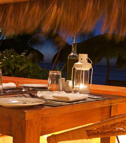 Romantic beachside dinner setup for two with lantern light and palm trees