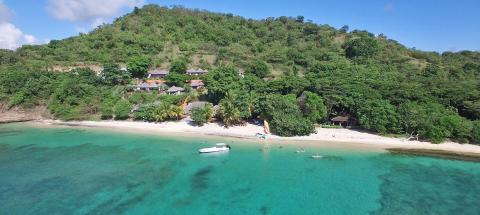 Tropical beach with clear waters, lush greenery, and resort amenities.