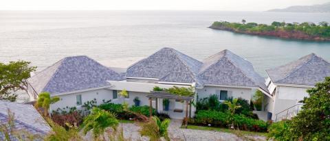 Luxurious coastal villas with white exteriors and lush greenery overlooking the ocean.