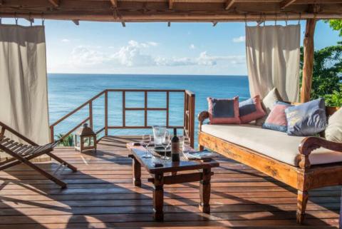 Luxurious ocean view deck with wooden furnishings and plush cushions.