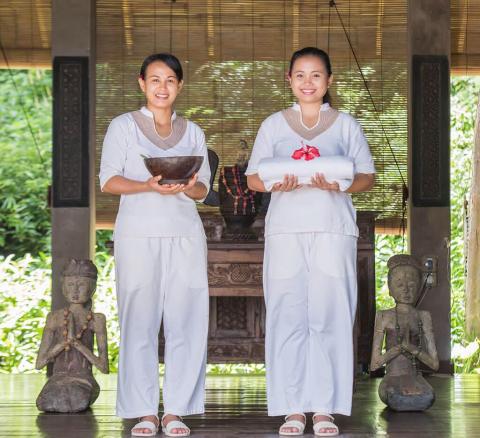 Traditional ceremony with women in white dresses holding sacred items outdoors