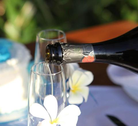 Pouring wine into glass beside white frangipani flowers, elegant setup
