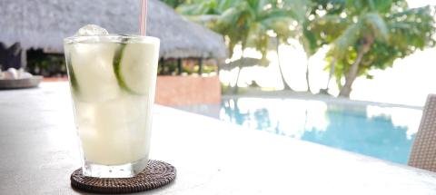 Cold drink with lime at poolside resort with palm trees