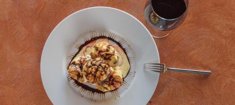 Elegant dessert with ice cream, chocolate syrup, raspberry coulis, and red wine