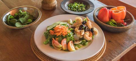 Assorted fresh culinary dishes on a rustic wooden table with seafood and salads.