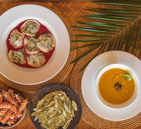 Gourmet dishes with dumplings, pasta, and creamy soup on woven table setting