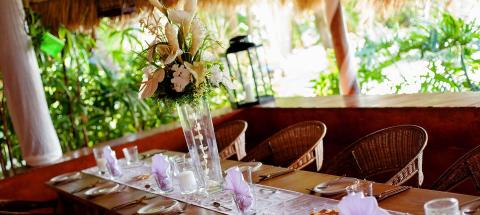 Elegant festive table setup with white flora, candles, seashells, and rattan chairs