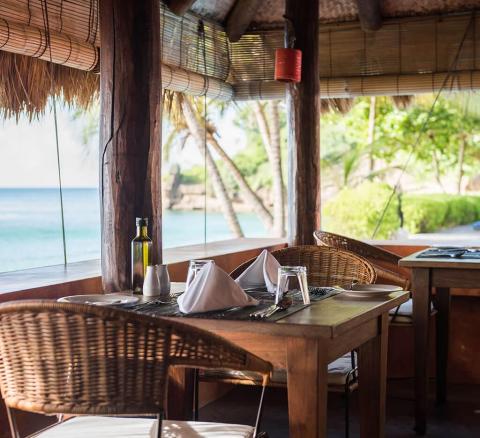 Beachside restaurant dining area with sea view and rustic wooden decor.