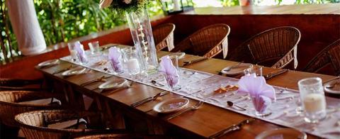 Elegant outdoor dining setup with floral centerpiece and wicker chairs on a patio