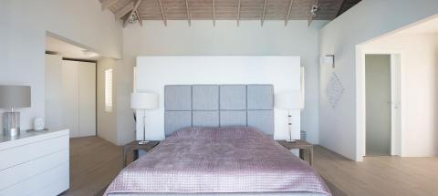 Modern minimalist bedroom with grey tufted headboard and purple bedspread.