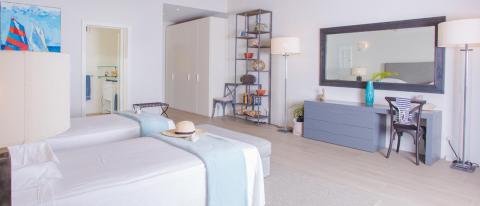 Modern twin bedroom with abstract art, bookshelf, and cozy blue accents.