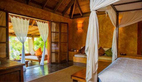 Rustic bedroom with four-poster bed and outdoor seating area