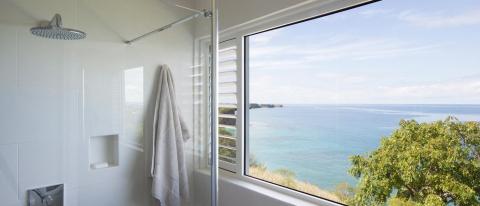 Modern bathroom with ocean view, rainfall shower, and white tiles