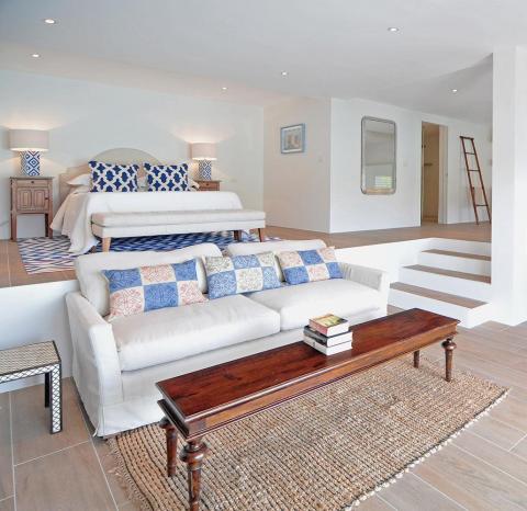 Stylish dual-purpose room with modern decor, elevated bed, and natural accents.