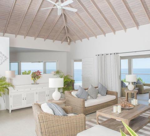 Seaside living room with ocean view, wicker furniture, and vaulted ceilings