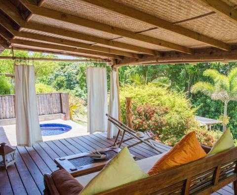 Cozy patio with wooden deck and chairs, outdoor bathtub amidst lush greenery