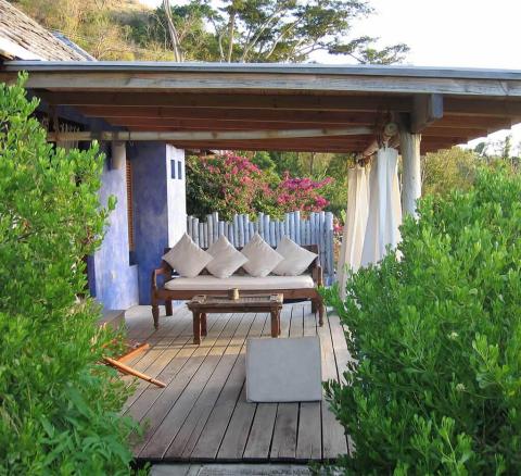 Serene outdoor lounge with wooden deck, pergola, and colorful cushions surrounded by greenery