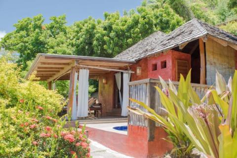 Cozy red house with veranda surrounded by tropical plants, ideal for relaxation