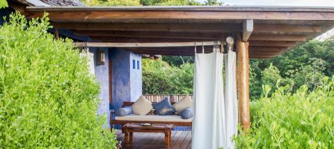 Secluded gazebo with daybed and lush greenery, ideal for relaxation and privacy.
