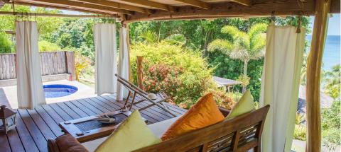 Tranquil outdoor living area with plunge pool, wooden bench, and ocean view