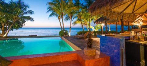 Luxurious pool and bar by tropical beach at twilight