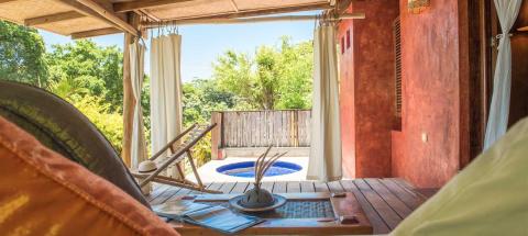 Serene vacation home with deck, white curtains, garden, and blue plunge pool.