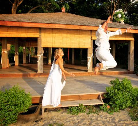 Joyful beach wedding scene with couple and sunset background.