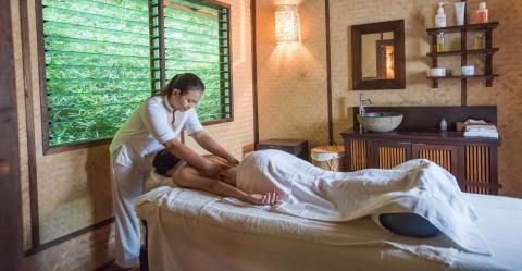 Therapist giving massage in serene spa room with lush greenery outside