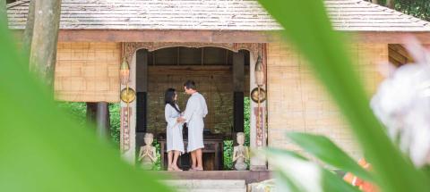 Couple in white robes sharing a moment on a porch with Asian decor