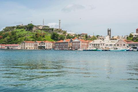 Colorful waterfront with colonial buildings and boats in a tropical harbor setting.