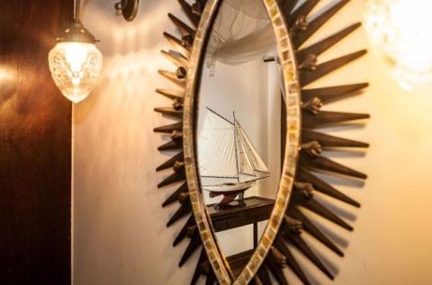 Sunburst mirror reflecting model sailboat in a vintage nautical themed room